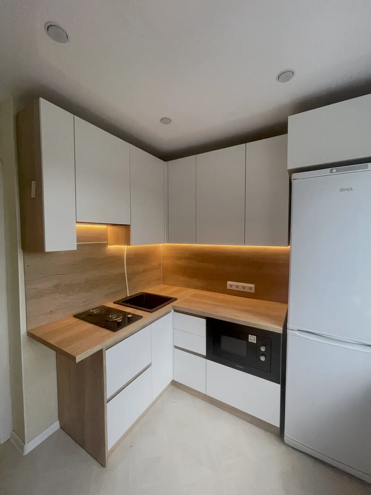 Угловая белая кухня с деревом